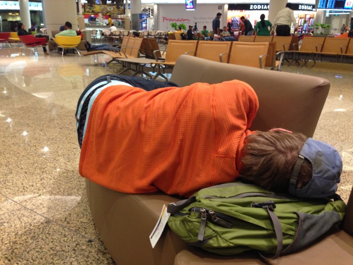 Brian sleeping on a hard "couch" at 3 AM in Mumbai's airport during a layover.